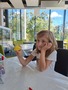 U stolu sedí holčička, která v pravé ruce drží žlutou rybičku poskládanou z papíru.