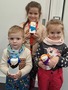 Na fotce jsou tři děti, které drží v ruce vyrobené sněhuláčky z papírových kelímků.